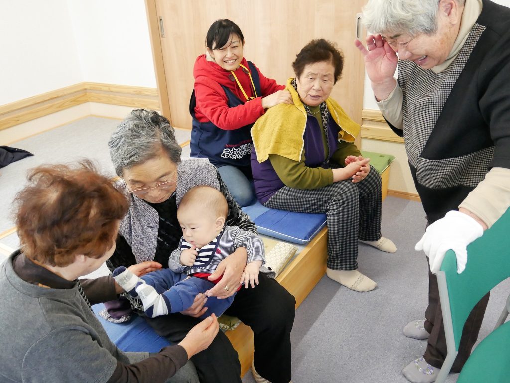 集会所のイベントで、赤ちゃんの抱っこの順番待ちをする住民さんたち